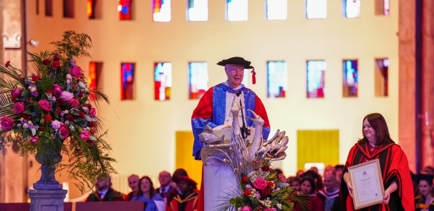 Fr Timothy Radcliffe delivers a speech from a lectern at Liverpool Metropolitan Cathedral wearing his honorary doctorate cap and gown.